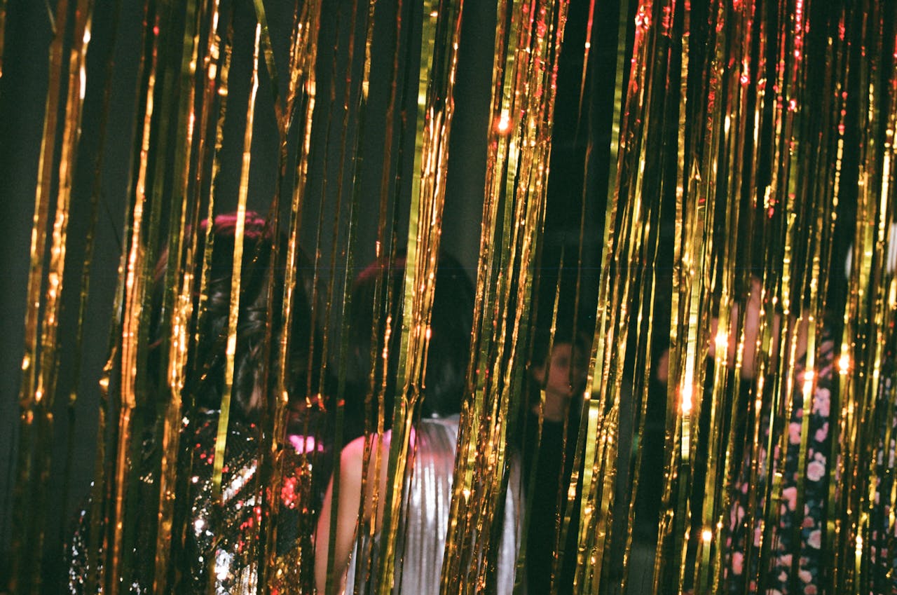 Elegant New Year's Eve party with gold tinsel and stylish evening wear, capturing a festive atmosphere.